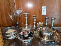 Photo showing twelve silver-plated items including candle holders, bowls, wine glasses with silver-plated bases, and a covered butter dish.