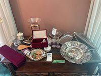 Assortment of trays, vases, platters, and utensils arranged on a dark wood table against a pink wall.