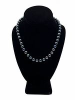 Frontal view of necklace on black velvet bust, showing full strand of pearls