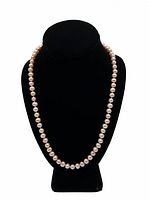 Front view of pink pearl necklace displayed on black bust