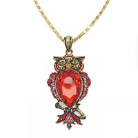 Front view of the owl pendant hanging on gold plated chain showing detailed red rhinestone and antique gold finish.