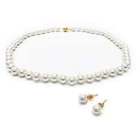 Pearl necklace and matching earrings laid out on a white background, showing the uniform pearls and gold-tone clasp and earring posts.