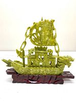 Front angle view showing the green glass dragon-headed longship with detailed deckhouse and sail on a wooden base.