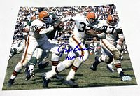 Full 8x10 photo showing Jim Brown running the football with an opponent attempting to tackle him. His signature and HOF 71 inscription visible in blue ink on the front.