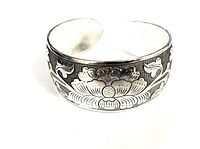 Close-up angle showing detailed flower motif engraving on the silver-tone metal bangle