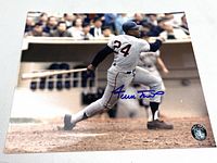 Angled photo of signed Willie Mays batting photo showing autograph and authentication sticker.