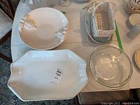 Image showing several ceramic platters, clear Pyrex glass casserole dish with lid, and white woven basket on table
