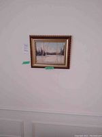 Photo showing the full framed oil painting of a winter landscape with birch and evergreen trees under a pale blue sky on a white wall.