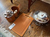 Photo showing all items together: silver plate flask set in brown container, composite cutting board, and silver plate ice bucket with lid