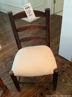 Front view of wood child's chair with light beige upholstered seat showing dark stained wood and two horizontal back slats.
