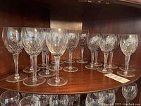 Seventeen crystal wine glasses arranged on wooden shelving, showing two distinct sizes.