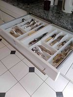 Top-down view of cutlery drawer showing all compartments filled with flatware and utensils