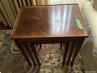Three wooden nesting tables stacked nested inside each other showing size and leg design.