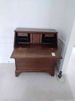 Front view of open drop-front desk showing interior cubbyholes, small drawers, center cabinet and lower drawers