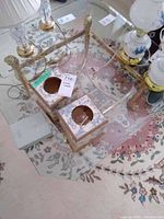 Photo showing two square decorative tissue boxes with blue floral patterns placed on glass and brass table.