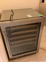 Front view of stainless steel beverage fridge with glass door closed and chrome handle