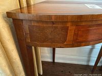 Close-up of side and veneer on the front corner of the triangular table showing wood grain and some chips.