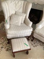 Wing chair and matching ottoman showing full front view, upholstery pattern, and wooden legs.