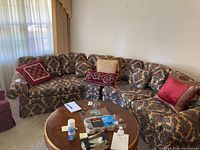 Two-piece sectional sofa arranged in an L-shape with multiple decorative pillows on it, showing overall condition and style.