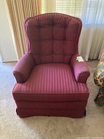 Red upholstered swivel armchair with high tufted back and curved padded arms