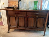 Front view of buffet showing two top drawers, four paneled cabinet doors, walnut finish, decorative glassware on top