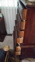 Wooden chest of drawers open showing multiple drawers with clothing inside
