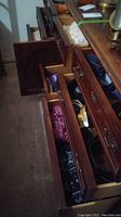 Wide view of open wooden drawers filled with bags, belts, and various fabric items