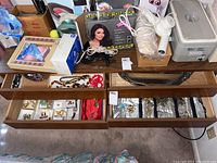 Overview of wooden drawers with jewelry inside, and various hair styling tools and storage boxes on the table top