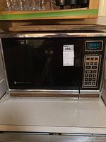 Front view of Magic Chef microwave oven showing numeric keypad, digital clock, and sticker label on door.