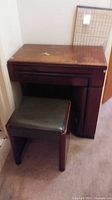 Wooden table with cushioned seat from side angle showing condition and size.