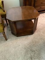 Full view of hexagonal wooden side table on carpeted floor, showing shape and general condition.