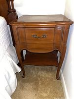 Front view of wooden side table with single drawer and decorative handle.
