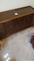 Full view of the large wooden stereo console showing front panel with four doors and wood grain finish.