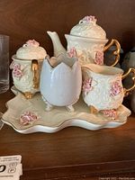 Porcelain tea set including teapot, sugar bowl, creamer, and tray with pink rose decorations and gold accents
