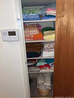 Shelves with stacks of assorted towels, table linens, and curtains folded and organized. Includes green, blue, orange, yellow, and pink patterned towels.