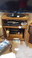 Full view of wooden TV cart with electronics and VHS tapes