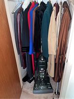 Vacuum and coats hanging in closet, walking canes visible
