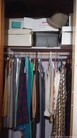 Image of closet showing hanging women's clothing including pants, skirts, and dresses in various colors including plaid and solid colors.