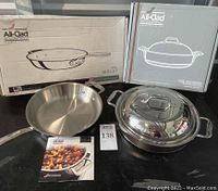 10-inch stainless steel skillet and 3-quart sauté pan with domed lid shown on black surface with their original boxes and product booklet.