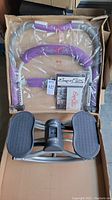 ExerFlex exercise machine parts unassembled, wrapped with purple foam grip parts visible, and manual in the box alongside Rock 'n Roll stepper foot pedals.