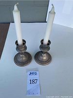 Pair of Gorham sterling weighted candlesticks each holding a white candle, shown from above on a white surface.