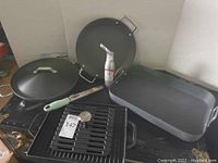 Calphalon crepe maker, wok/saucepan with lid, roasting pan, and grill with press shown together