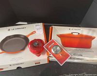 All four pieces grouped: orange Coquelle box, generic skillet box, red apple casserole, replacement knob
