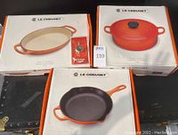 Overhead view of three Le Creuset cookware boxes and replacement knob