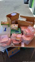 Multiple Lock&Lock pink-lidded food storage containers stacked and nested on a table outdoors, some in box packaging.