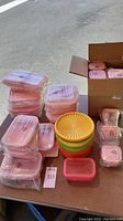 Pink Lock&Lock containers shown stacked in various sizes and sealed in original packaging alongside three vintage round Tupperware bowls with lids in harvest colors.
