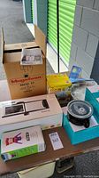 Wide view of all items in lot on table including boxes and packaging.