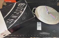 Closed oval cocotte next to its original black Staub box