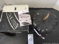 View of Staub 3.5 qt black enameled cast iron pumpkin casserole dish with lid, original box and instruction manual