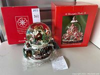 Photo of both Christopher Radko snow globes with original boxes, Santa Express snow globe with visible musical feature tag and plastic wrapping.